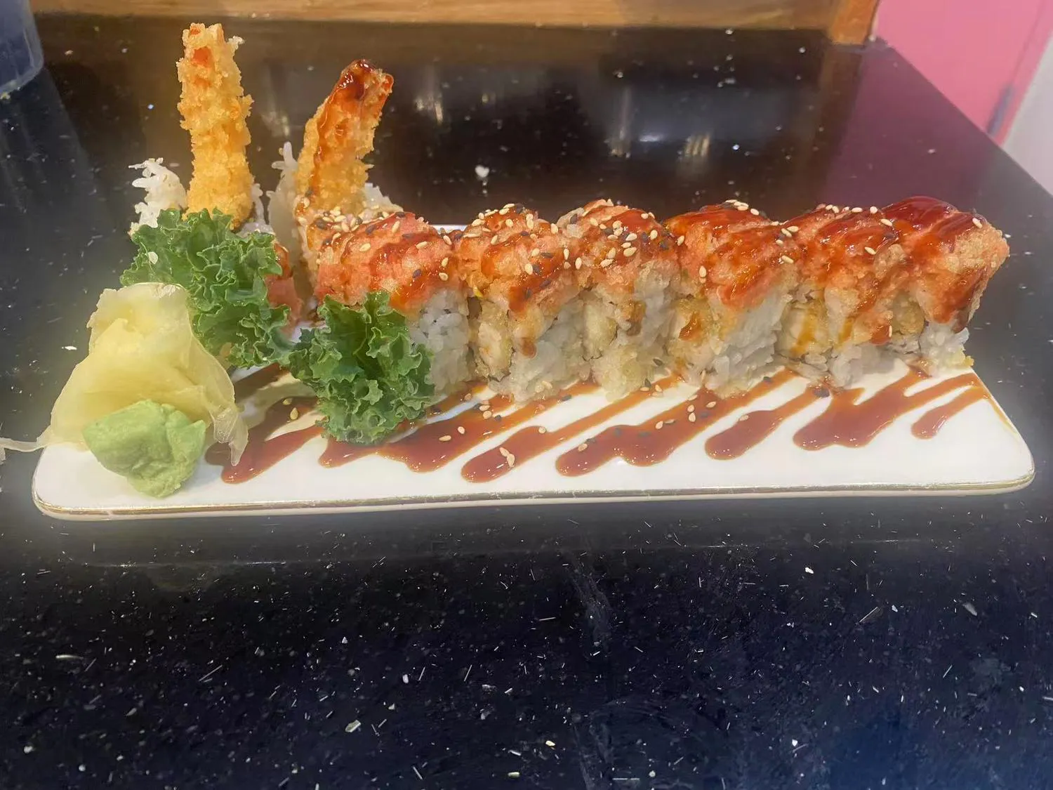 Shrimp tempura sushi roll with spicy sauce on white plate at Kumo Sushi & Hibachi, a Japanese Restaurant in Alachua