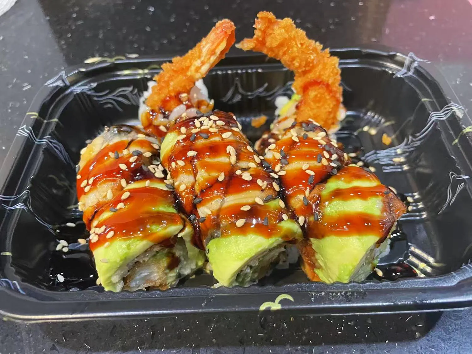 Shrimp tempura avocado roll with eel sauce in takeout container at Kumo Sushi & Hibachi, a Japanese Restaurant in Alachua